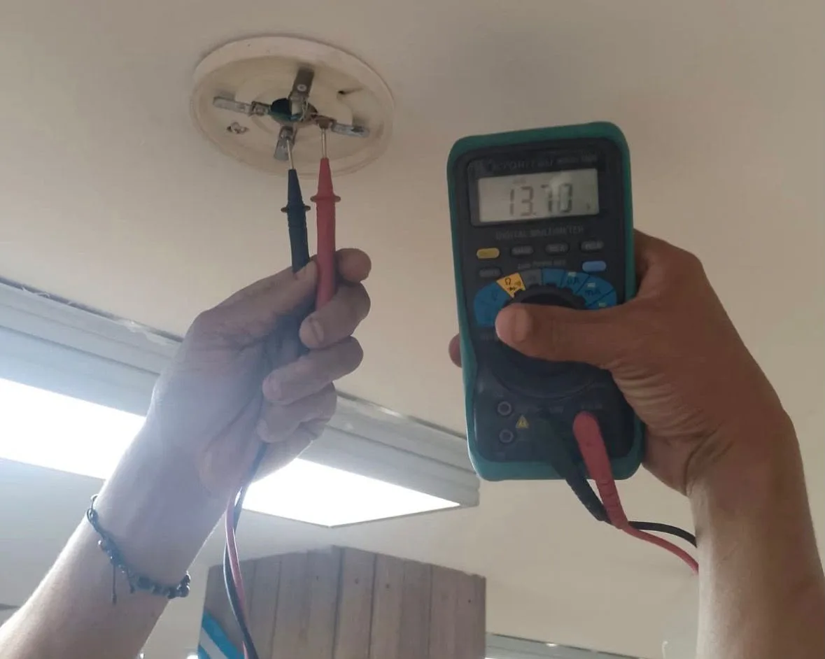 Técnico verificando detector de humo con multímetro